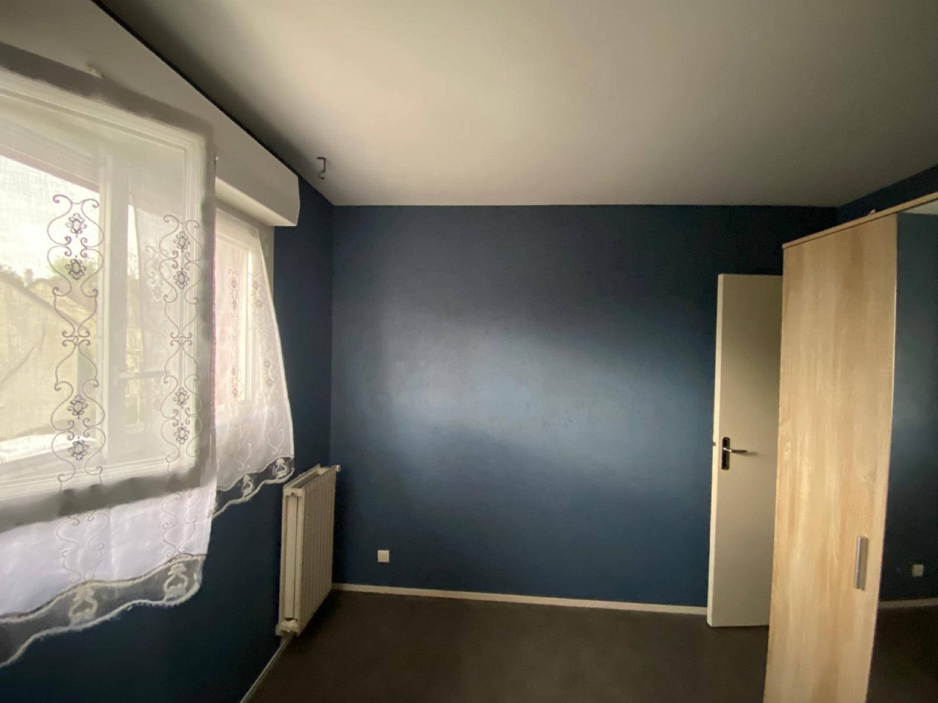 Chambre repeinte avec un mur d'accent bleu canard et un plafond blanc, finition mate soignée